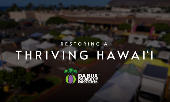 Title screen for the DA BUX video Restoring A Thriving Hawaii with text over a video of a drone shot of the Waianae Farmers Market.